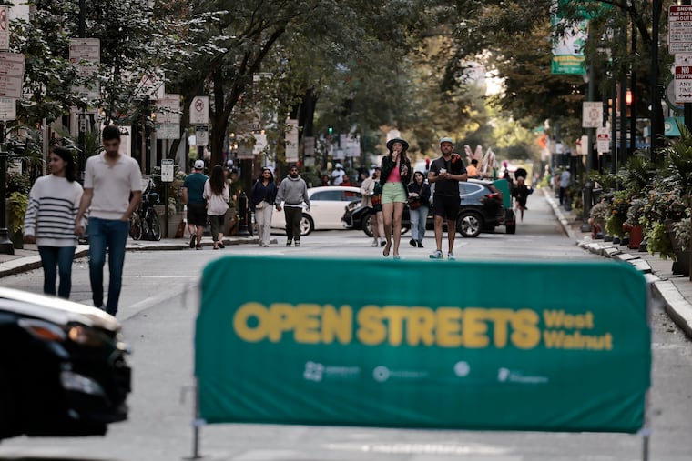 People stroll the 1600 block of Walnut Street during the Open Streets: West Walnut event in Philadelphia on Sunday, September 8, 2024. The car-free streets pilot is returning to seven blocks of the retail district near Rittenhouse Square on Dec. 8 and Dec. 15 for holiday shopping.