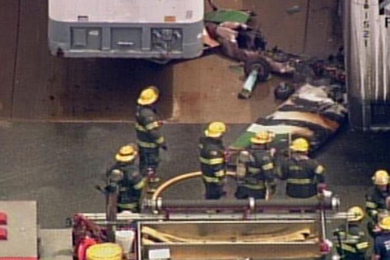Firefighters examine plane's wreckage, some of which came to rest under a tractor trailer. (Photo courtesy of NBC10)