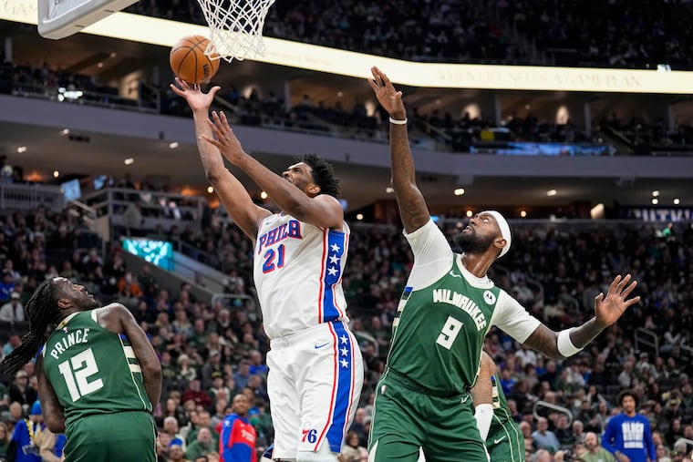 Sixers center Joel Embiid goes to the hoop between Milwaukee's Taurean Prince (12) and Bobby Portis on Sunday.