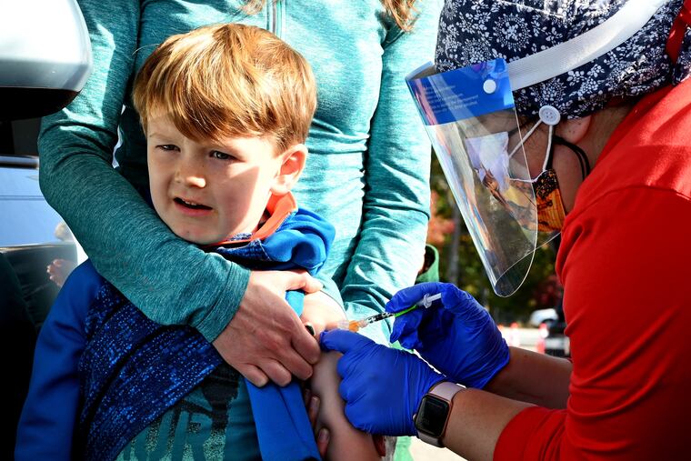 Amanda Moon of Haddonfield holds her son Lucas, then 6, as Cooper University Health Care nurse educator Christina Polizzi (right) administers his shot at the Camden County drive-thru pediatric COVID-19 vaccine clinic last year.