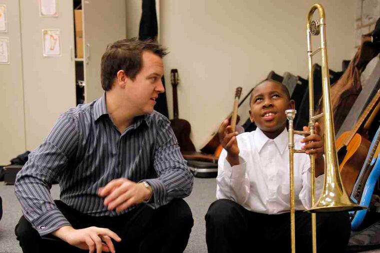 Tune Up Philly music instructor Joshua Popejoy with Khiyam Hayes, 9, before a Dec. concert. A deep bond with classical music - and thus orchestras - is best developed early in life.