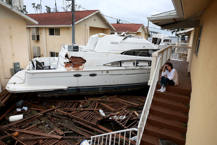 A woman in Florida sits next to a boat that Ian pushed against her apartment. It won't be as bad around here, but the Shore is in for several days of strong onshore winds.