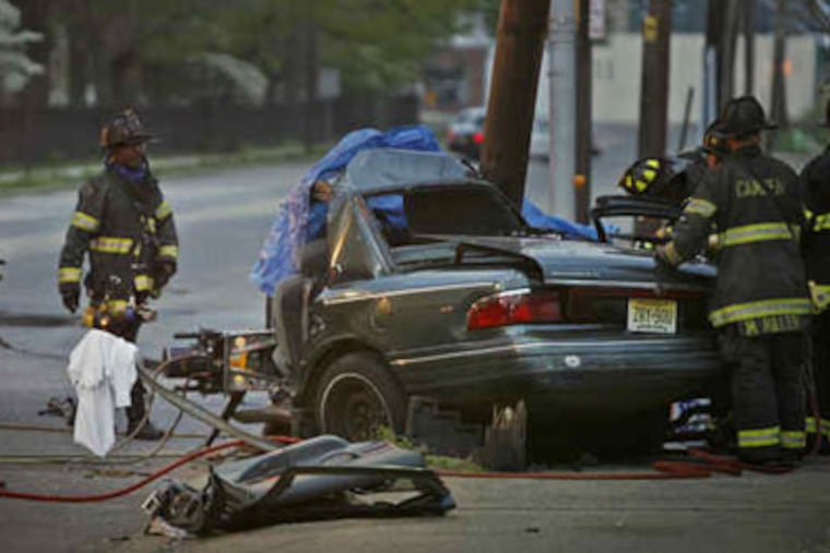 Members of the Camden Fire Department work to remove a body from a Mercury Grand Marquis that crashed into a pole on Haddon Avenue. (Alejandro A. Alvarez/ Staff Photographer)