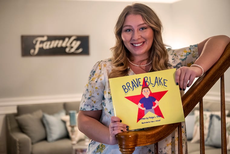 Rowan University inclusive education major Paige Starr, poses with her children's book Feb. 22, 2022. "Brave Blake” is about a boy who learns how deal with the fact he looks different from other kids. It was inspired by her youngest brother Blake, who has a cleft lip, and has always been comfortable with who is and how he looks. The cover and illustrations are by Talia Metcalf.