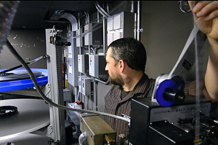 At the nonprofit Hiway Theatre in Jenkintown, Michael Kost threads 35mm film. "If we don't have a digital projector," said a top Hiway official, "we will not be able to participate in the movie industry." TOM GRALISH / Staff Photographer