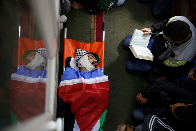File - In this Tuesday, Dec. 4, 2018 file photo, Palestinians pray by the body of Mohammed Habali 22, during his funeral in the Tulkarem refugee camp near the West Bank city of Tulkarem. The Israeli military says it has opened an investigation into the death of Habali after a video surfaced appearing to show him being shot in the back. The security-camera video shows Habali walking in an alleyway holding a stick when he is shot from behind and falls down on his face. (AP Photo/Majdi Mohammed)