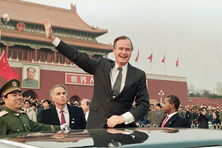 In this 1989 file photo, then-President George H.W. Bush stands on his car and waves to crowds in Tiananman Square in Beijing. Chinese state media are praising Bush this week as a "statesman of vision," recalling the late president's role in helping end the Cold War and establishing policies toward China.