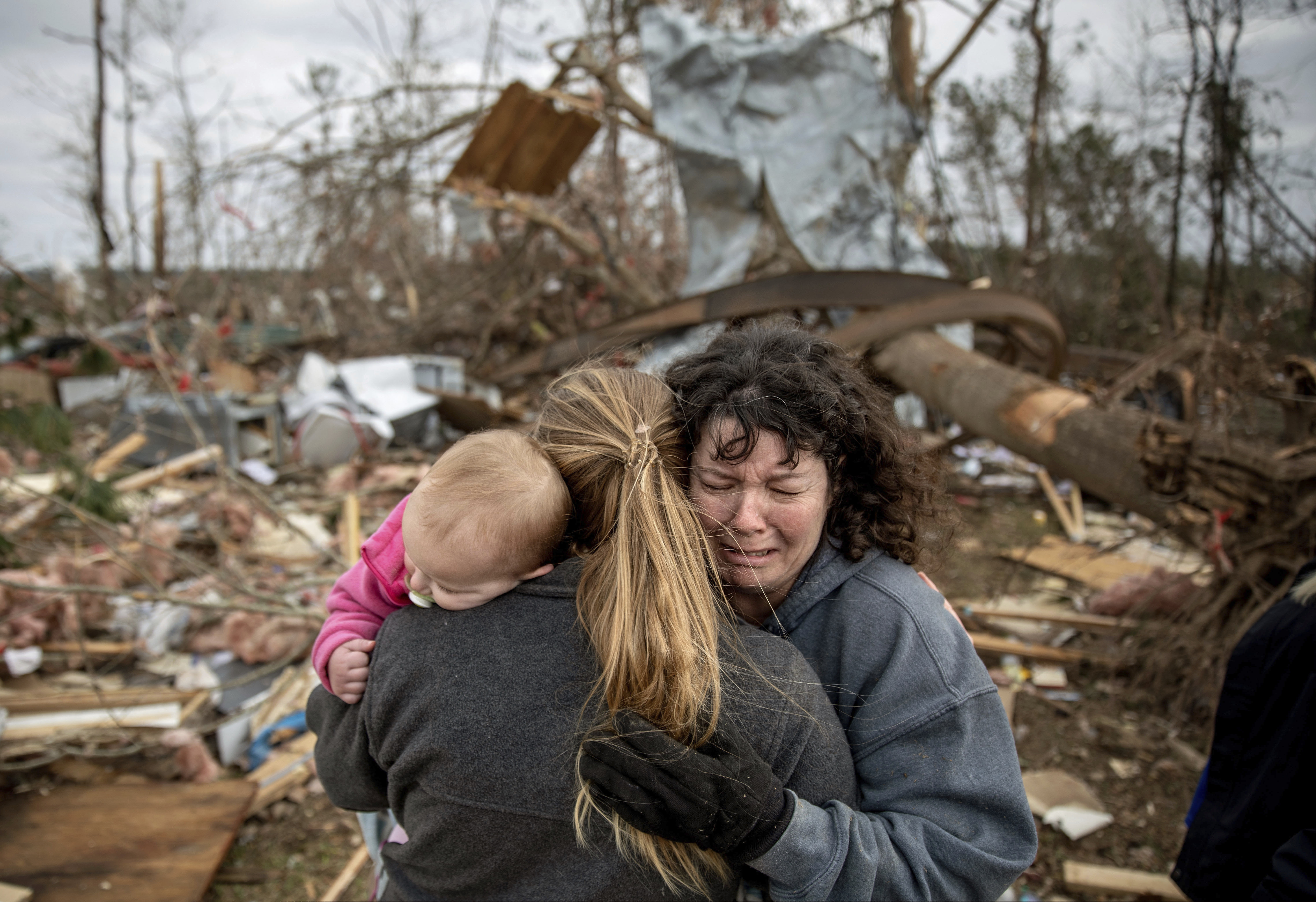 Carol Dean (right) cries while embraced by Megan Anderson and her 18-month-old daughter, Madilyn, as Dean sifts through the debris of the home she shared with her husband, David Wayne Dean, who died when a tornado destroyed the house in Beauregard, Ala., Monday, March 4, 2019. "He was my wedding gift," said Dean of her husband whom she married three years ago. "He was one in a million. He'd send me flowers to work just to let me know he loved me. He'd send me some of the biggest strawberries in the world. I'm not going to be the same."