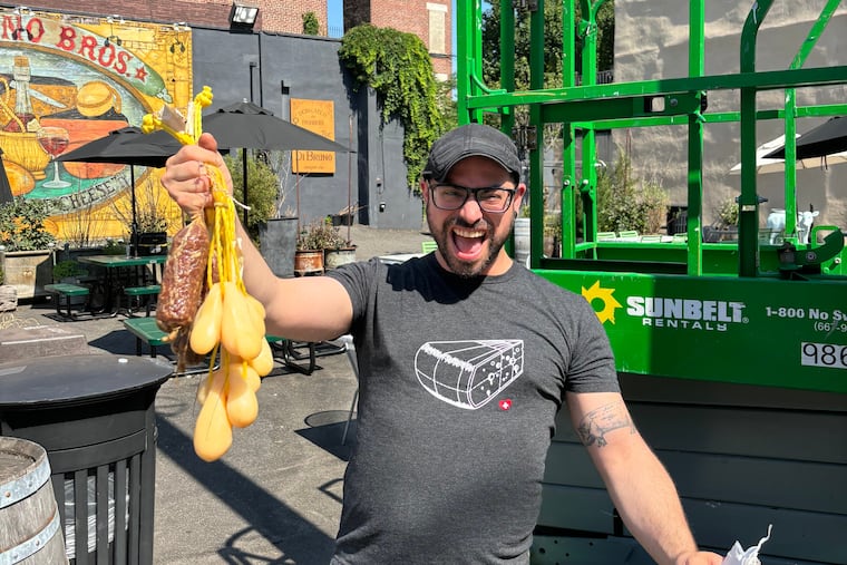 Tommy Amorim, a multi-unit cheese specialist at Di Bruno Bros., climbed atop a crane Thursday to rescue stranded meat and cheese left behind from last month's grease pole climbing competition. The aging prizes went right in the garbage.