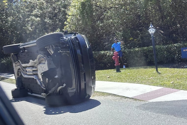 Golfer Tiger Woods stands by his overturned vehicle in Jupiter Island, Fla., last Friday.