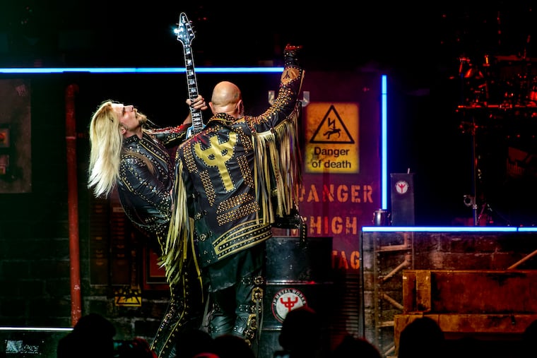 Frontman Rob Halford, with the band’s logo on his back, and guitarist Richie Faulkner (left) are on stage as the Judas Priest 50 Heavy Metal Years tour stops at the Met in North Philadelphia Mar. 29, 2022.
