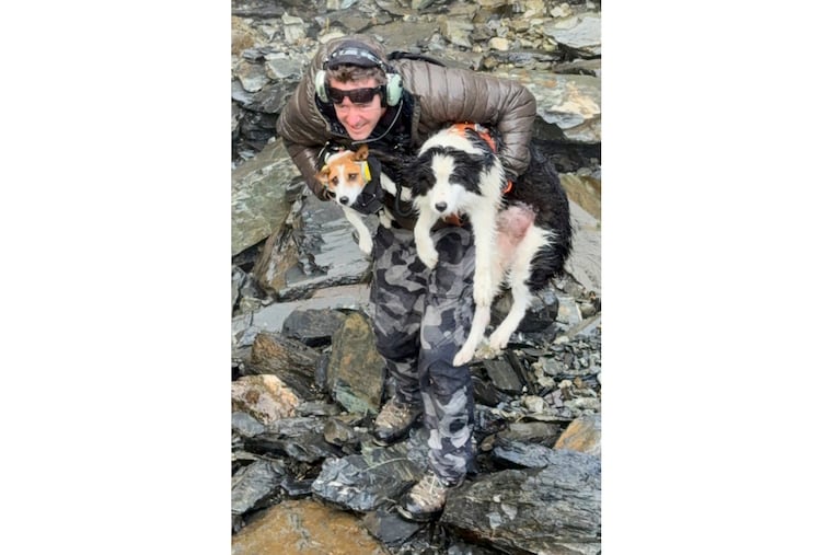 In this photo released by Precision Helicopters Ltd, Wayne Holmes holds his dog Bingo (left) after the rescue of Molly at a waterfall on the Arahura River on the West Coast of the South Island of New Zealand, on Tuesday.