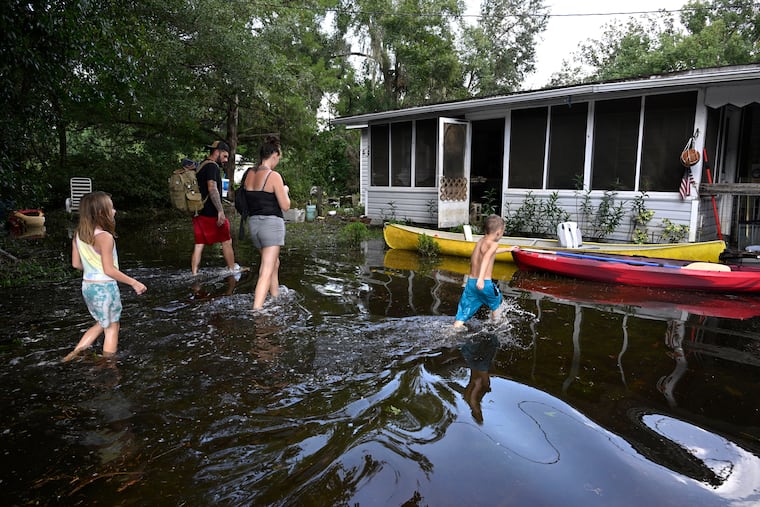 Dustin Holmes, his girlfriend Hailey Morgan, and her children Aria Skye Hall, 7, and Kyle Ross, 4, arrive to their flooded home in the aftermath of Hurricane Helene on Friday in Crystal River, Fla.