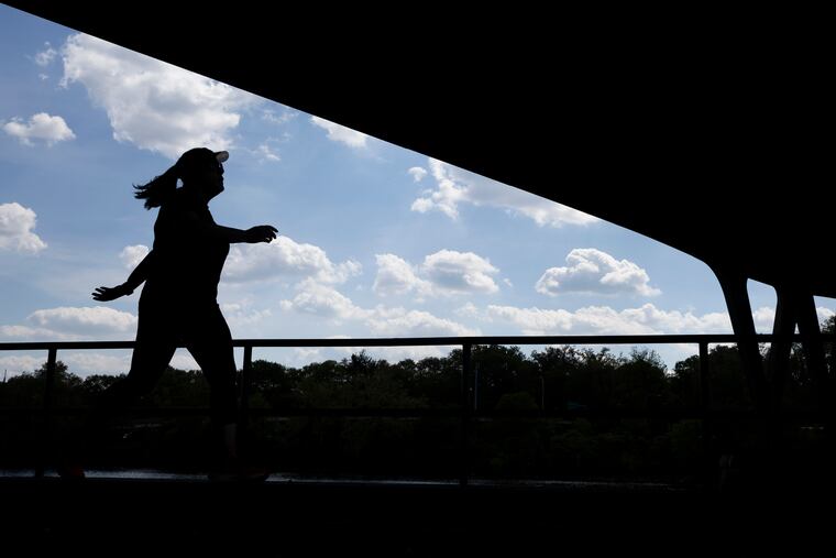 A runner moves along the Schyulkill River Trail under the Girard Avenue Bridge in Philadelphia on May 1, 2024.