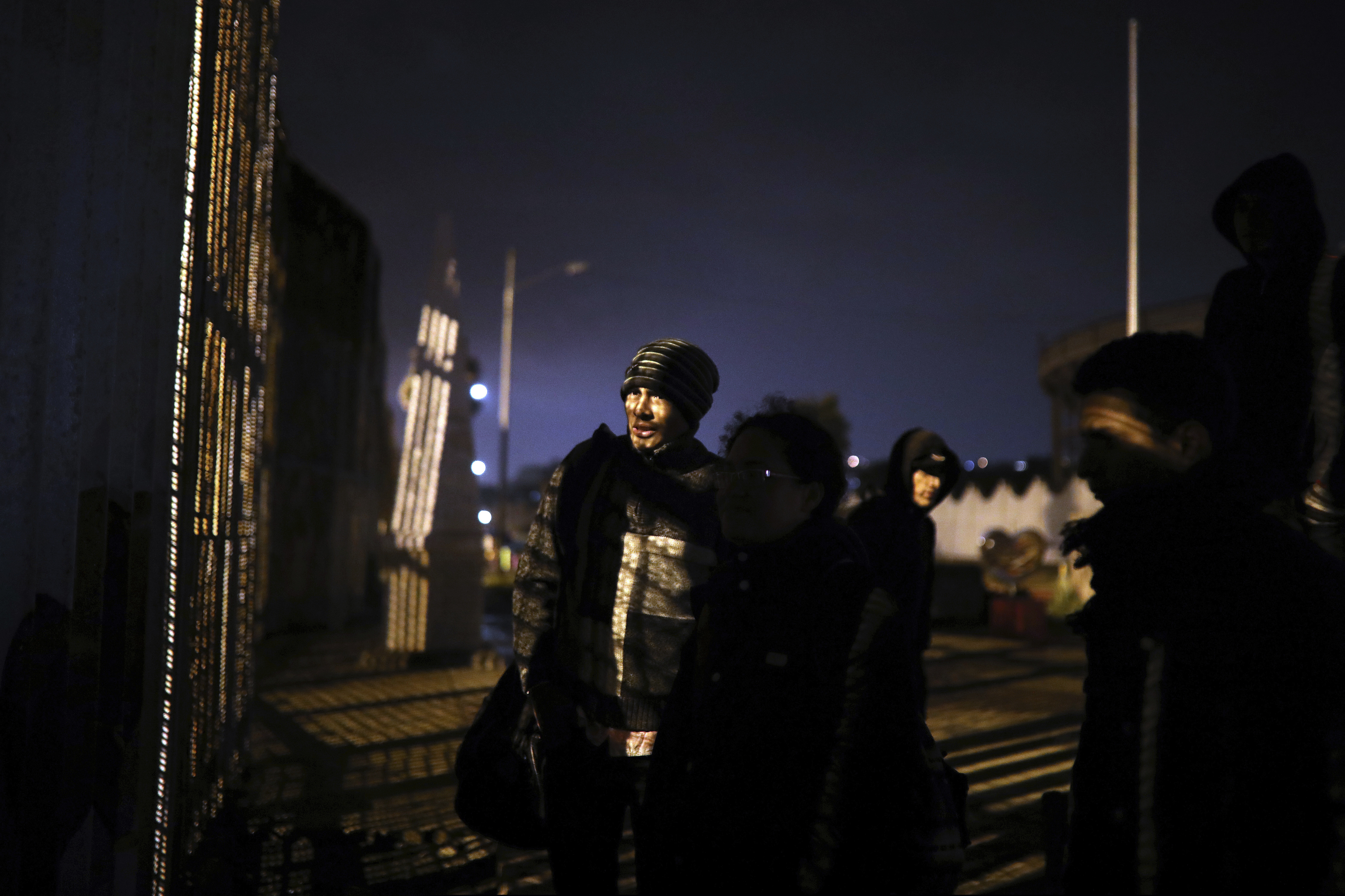 Honduran migrants stand at the border wall in Tijuana, Mexico, Friday, Nov. 30, 2018, before crossing over. The group was detained by U.S. Border Patrol agents as soon as they stepped onto U.S. territory. Thousands of migrants who traveled via a caravan members want to seek asylum in the U.S. but may have to wait months because the U.S. government only processes about 100 of those cases a day at the San Ysidro border crossing in San Diego.