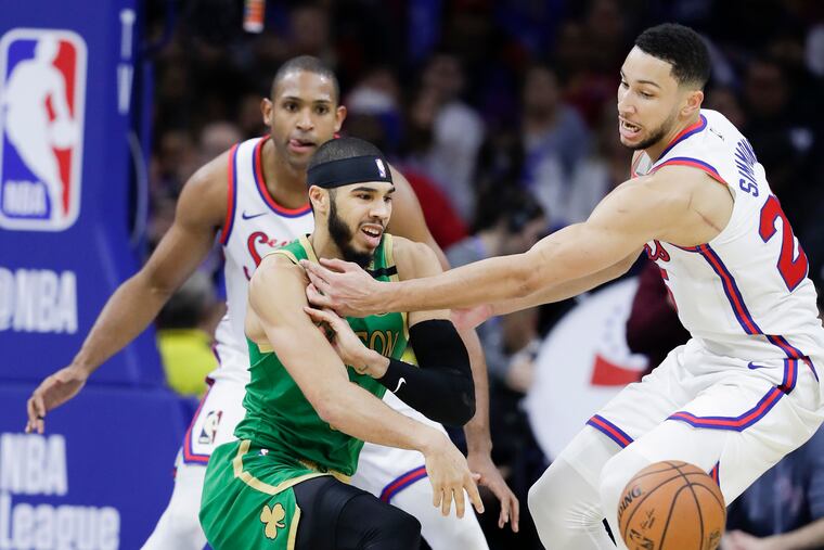 Boston Celtics All-Star forward Jayson Tatum passes the basketball while being defended Sixers All-Star guard Ben Simmons and center Al Horford on Jan. 9.