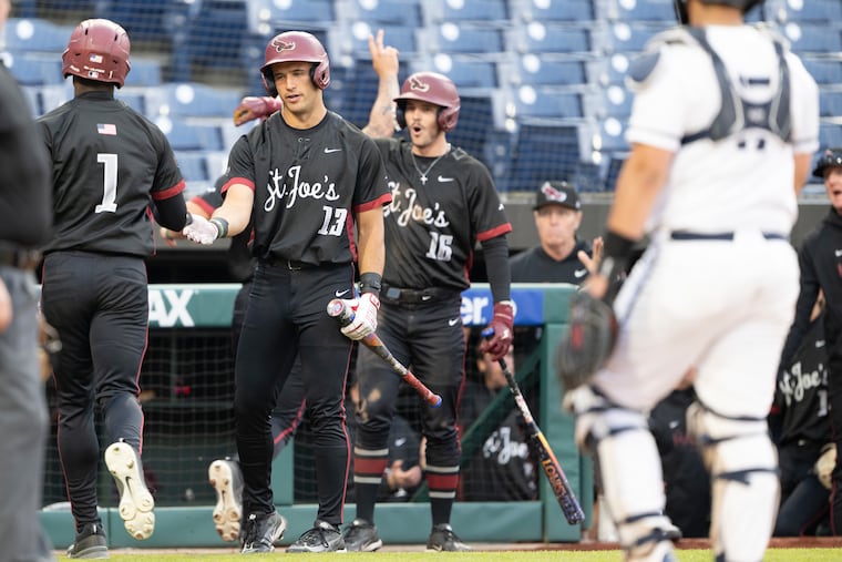 St. Joseph’s Richard Beggy is congratulated at home plate after scoring a run in the third inning against Penn during the Liberty Bell Classic at Citizens Bank Park on Tuesday.