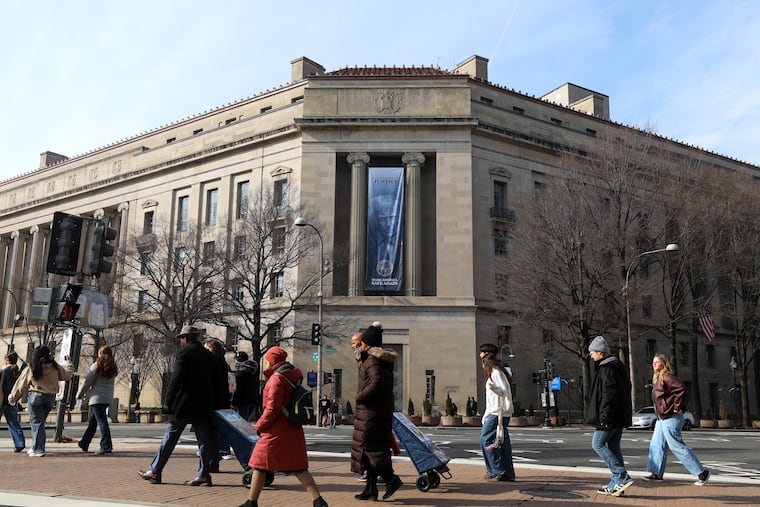 Tourists walk past a banner with President Donald Trump hanging on the Department of Justice on Feb. 27.