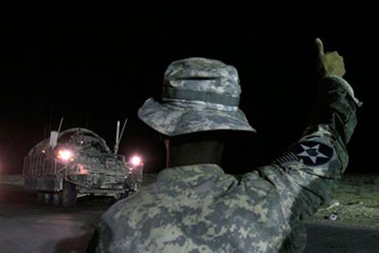 An Army soldier gives a thumbs-up to the crew of the last Stryker armored vehicle to leave Iraq and enter Kuwait. (Maya Alleruzzo / Associated Press)