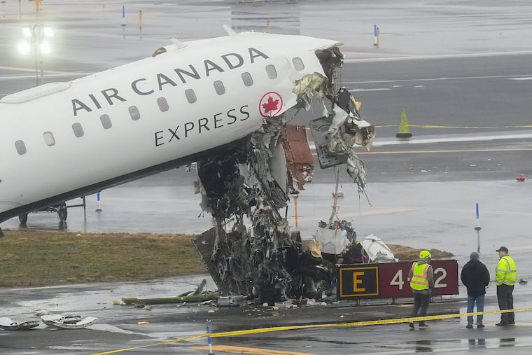 Officials investigate the site where an Air Canada jet came to rest after colliding with a Port Authority firetruck at LaGuardia Airport, shortly after landing March 23 in New York.