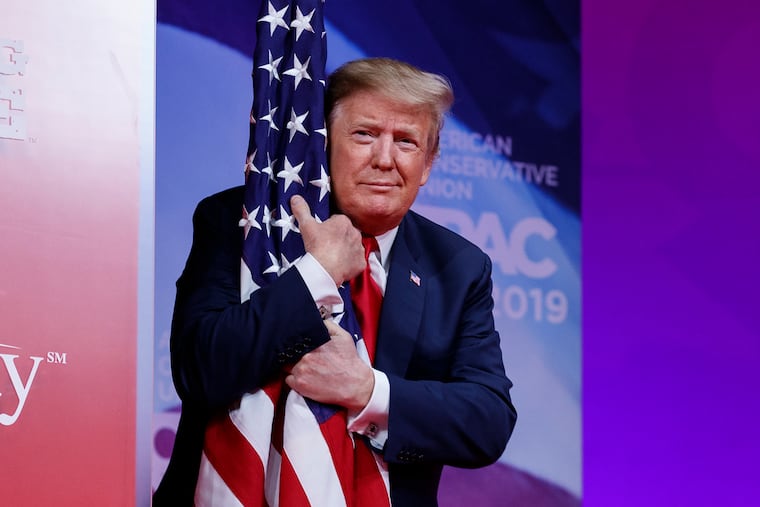 President Donald Trump hugs the American flag as he arrives to speak at Conservative Political Action Conference, CPAC 2019, in Oxon Hill, Md., Saturday, March 2, 2019.