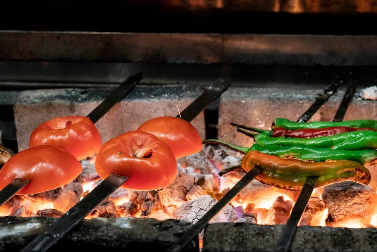 Charred long hots, tomatoes and onions on the grill, at Suraya.