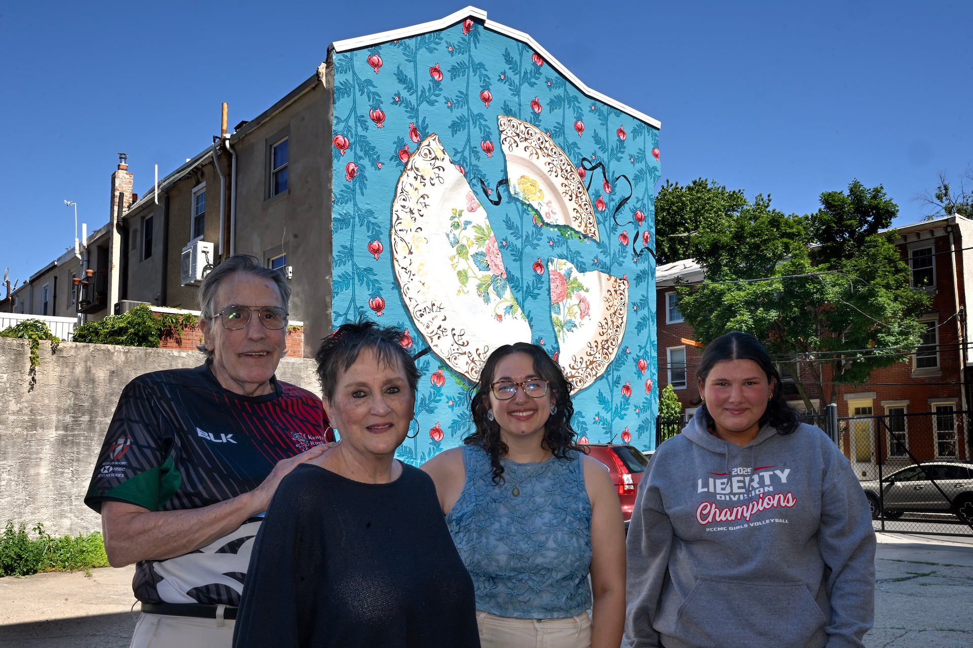 Homeowners Sara and Clark DeLeon (left) and their granddaughter Lucy Metzker (right) pose in front of their mural with artist Sammy Kovnat (center).