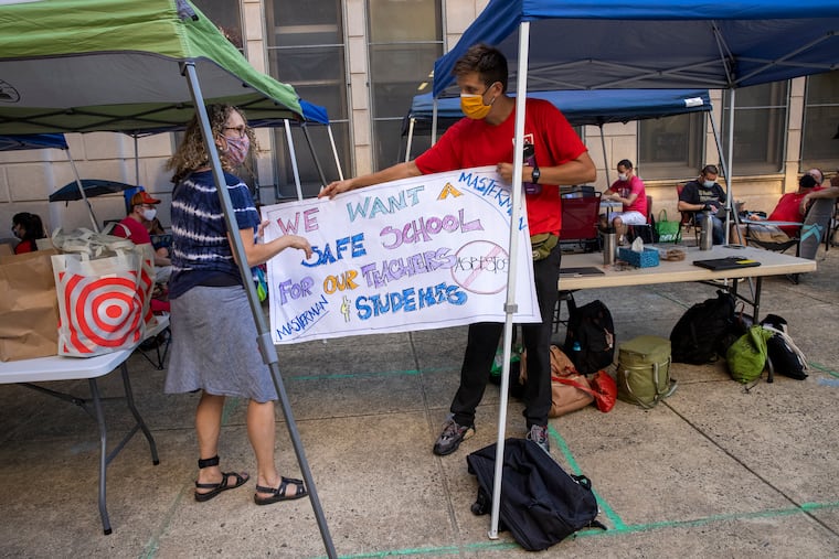 A Masterman parent presented a sign to Ethan Tannen, a Masterman teacher, as Tannen and dozens of other teachers worked outside the school on Aug. 26, 2021. The teachers refused to work inside because they felt they did not have enough information about asbestos inside the building. Tannen and two other teachers have filed a class-action lawsuit against the district over discipline they received and withheld pay.
