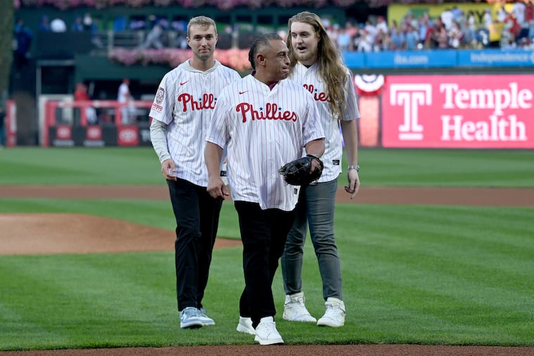 Former Phillies catcher Carlos Ruiz (center) walks with the sons of Roy Halladay, Braden (left) and Ryan, after throwing out the first pitch before Game 2 on Monday.