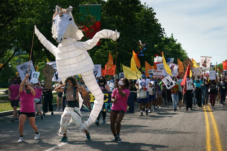 Samantha Rise, program director at Girls Rock Philly (at the base of a unicorn puppet), marches on the Benjamin Franklin Parkway during an arts event organized by the Artist Coalition for a Just Philadelphia on June 16.