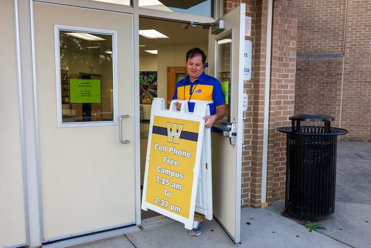 John DiMarco places a sign outside the junior high entrance for students at Woodbury Junior and Senior High School informing parents their children’s phones are locked during school hours. This program to keep kids off their phones during school started this school year.