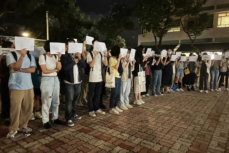 Protesters hold up blank white papers during a commemoration for victims of a deadly fire at the Chinese University of Hong Kong on Monday.