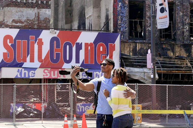 Allen Haynes and DeAnne White, visiting from Queens, N.Y., snap a picture across from the Suit Corner. Fire destroyed the building just weeks after its neighbor, the Shirt Corner, collapsed.