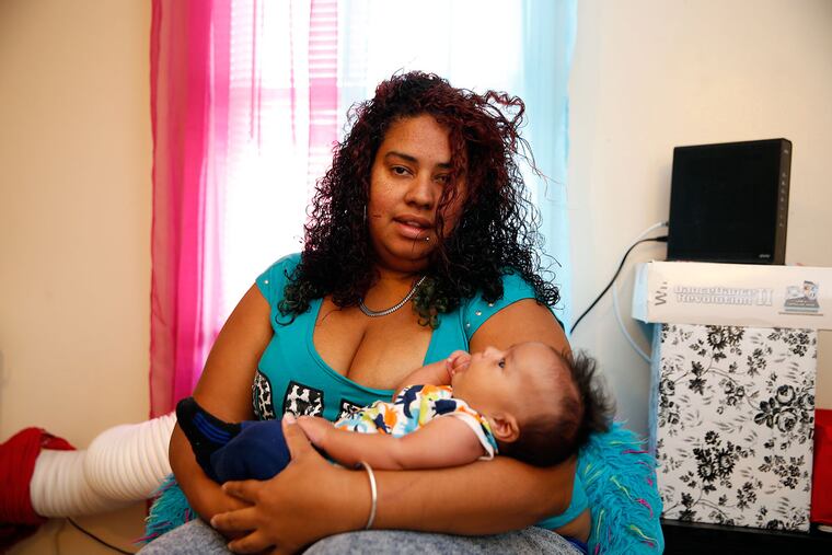 Carmen Rios holds her son, Jetxiel, in her apartment. The mother of four, who relocated to Camden last year, says the city is safer than Puerto Rico.