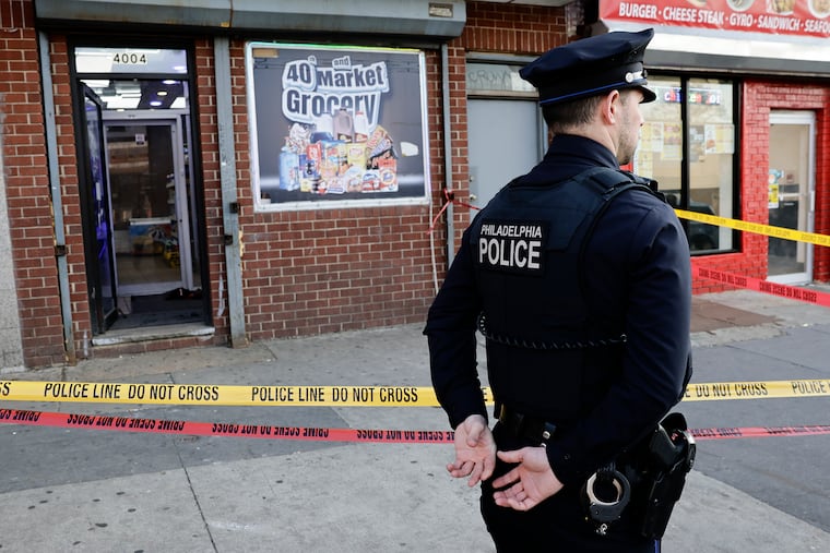 A Philadelphia police officer stands outside the 40th and Market Grocery store after a 26-year-old man was fatally shot on Monday.