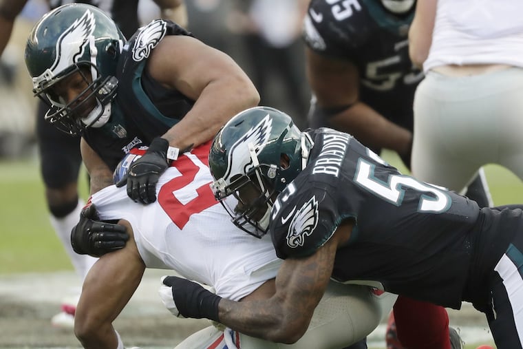 Michael Bennett (top) and Nigel Bradham take down Saquon Barkley during the Eagles' win on Sunday. Bradham broke his thumb during the game.