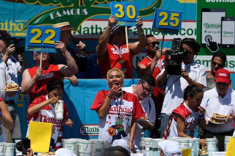 Juliet Lee, left, Miki Sudo, center, and Michelle Lesko, right, compete in the closing moments of the women's competition of the Nathan's Famous July Fourth hot dog eating contest, Thursday, July 4, 2019, in New York's Coney Island.