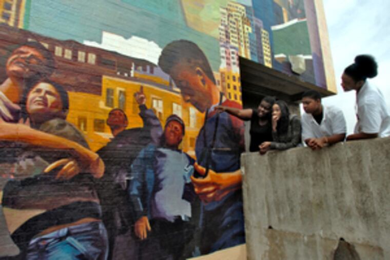 At Olney High, (from left) Monica Mathieu , 17; Yvonne Fuller, 17; Ombray Grigsby, 18, and Chrishten Brooks, 17, look over "Common Ground: The Global Heritage Project," which they helped paint. Mathieu is painted at center, under the upraised arm.