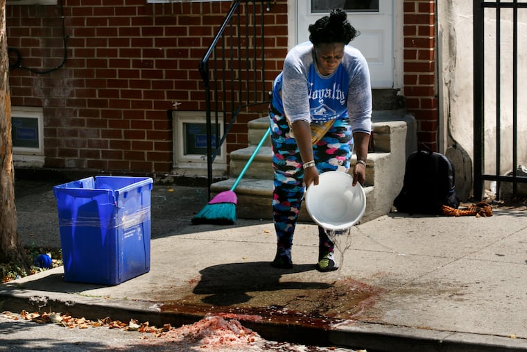 A woman who prefers to be identified by her nickname "Tank", cleans blood off of the sidewalk on the 2100 block of North 4th Street, Tuesday, July 17, 2018. Multiple people were shot on this block late last night.