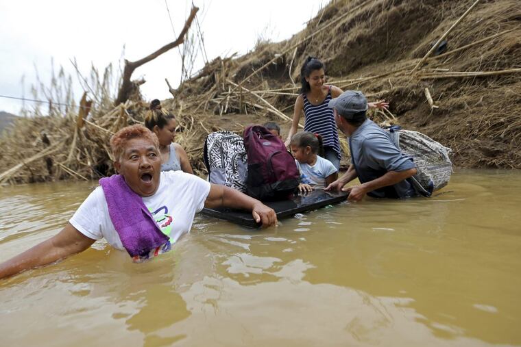 On Wednesday, Marta Sostre Vazquez gasps as she starts to wade into the San Lorenzo Morovis river with her family, after the bridge was swept away by Hurricane Maria, in Morovis, Puerto Rico. The family was returning to their home after checking on family on the other side of the river.