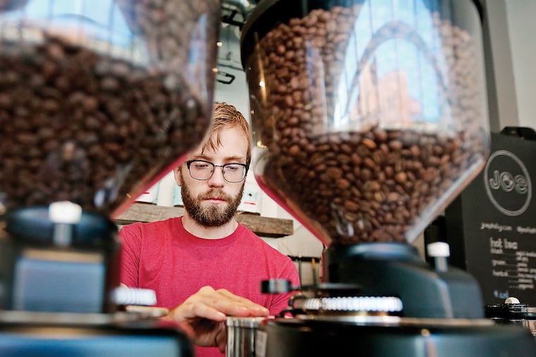 Barista David Thompson grinds coffee beans at Joe Coffee on the 3200 block of Chestnut Street in University City. The small chain received loans from Bond Street to open two outlets in Manhattan. (DAVID MAIALETTI/Staff Photographer)