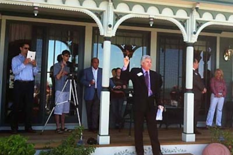 Auctioneer Todd Wohl conducts the proceedings on the bayside veranda of the house.
