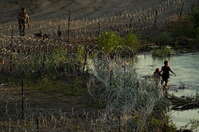 Migrants walk along concertina wire as they try to cross the Rio Grande at the Texas-U.S. border in Eagle Pass, Texas, last week.