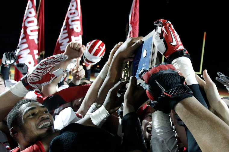 Delsea players all try to touch their championship prize. ( RON CORTES / Staff Photographer )