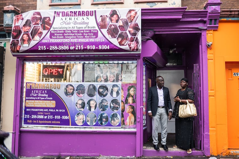 Eric Edi (left), of Africom, and Fatou Mbow (right), owner of N’Darkarou African Hair Braiding and Philadelphia Hair Braiding, stand outside the shop along Frankford Avenue in July. On Oct. 17, Gov. Josh Shapiro signed Act 100 of 2024 into law, eliminating onerous hair braiding regulations that impacted businesses like Mbow's. Edi has been working to see such a law passed since 2018.