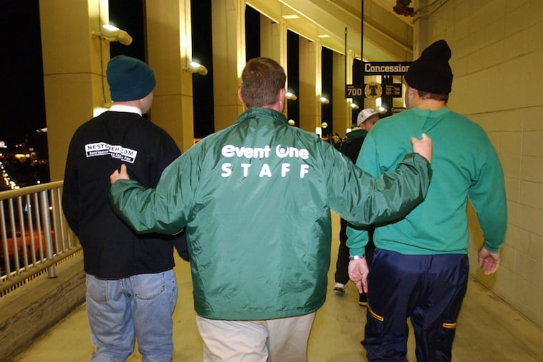 A stadium security member escorts two fans out of the Vet after they urinated on the wall in the 700 Level in 2002.