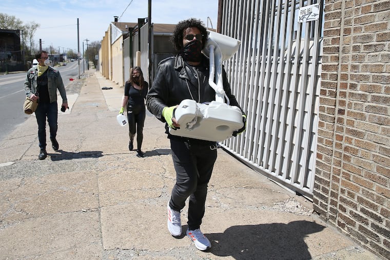 Colin Morgan, right, and his friends, Owen Mercurio, left, and Beth Boyle, center, prepare to install a portable sink for homeless people to use on 49th Street near Grays Avenue in Philadelphia, Pa. on April 28, 2020.