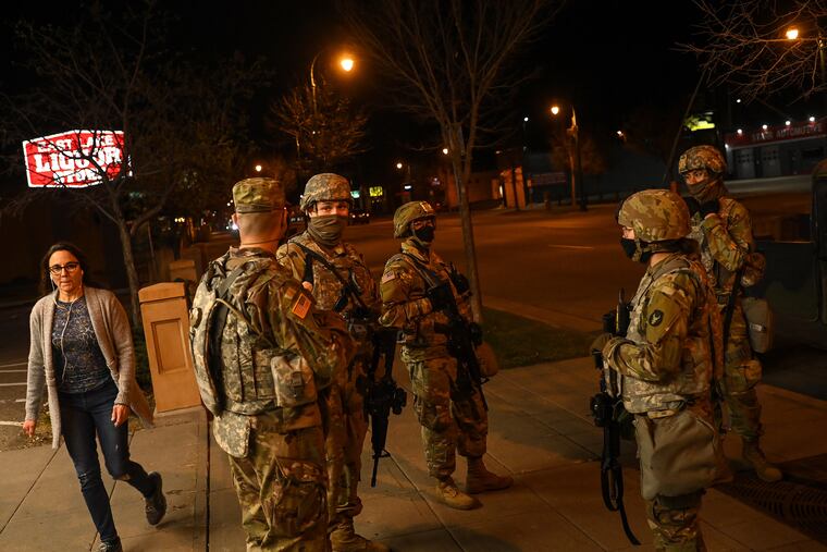 A pedestrian walking past members of the National Guard in Minneapolis on Friday.
