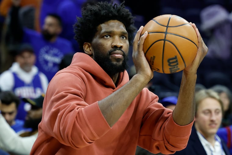 Sixers center Joel Embiid shoots the basketball in street clothes after the Sixers beat the Orlando Magic on Friday.