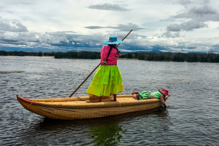 A young woman poles through the shallow waters of Lake Titicaca in Peru. Uros Titino, one of the lake's famed floating islands, is home to the Uros, who live close to the shoreline where the reeds grow — their huts and boats are substantially made from reeds — and the lake is no more than 10 feet deep.